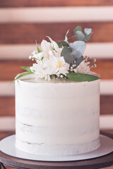 a white wedding cake on a table with leaves and flowers decoration