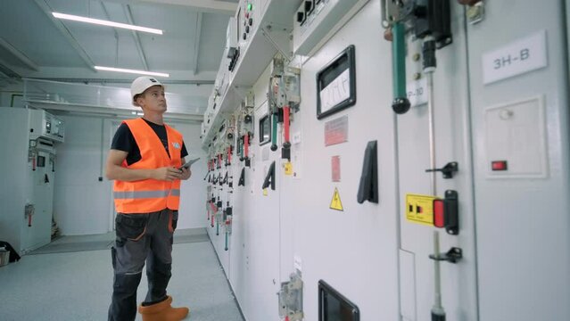 Electrical engineer working check the electric current voltage and overload at front of load center cabinet or consumer unit for maintenance in main power distribution system room.