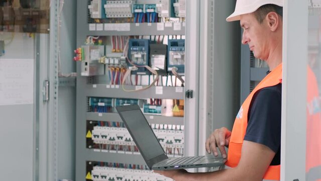 Electrical engineer working check the electric current voltage and overload at front of load center cabinet or consumer unit for maintenance in main power distribution system room.