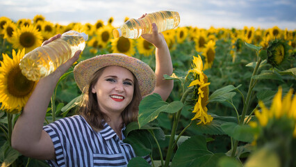 Beautiful smiling joyful middle-aged farmer woman holding bottles of golden sunflower oil in her...