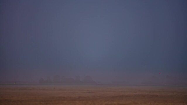A misty fog creeps in over farmland then a super moon rises an illuminates the countryside - time lapse