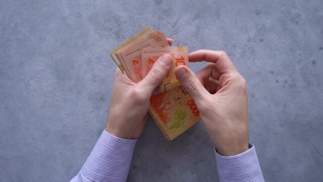 Business person counting Argentine cash. Top view.