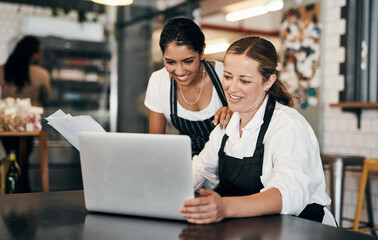 Cafe employees working on a laptop while planning budget strategy online. Happy coffee manager and...