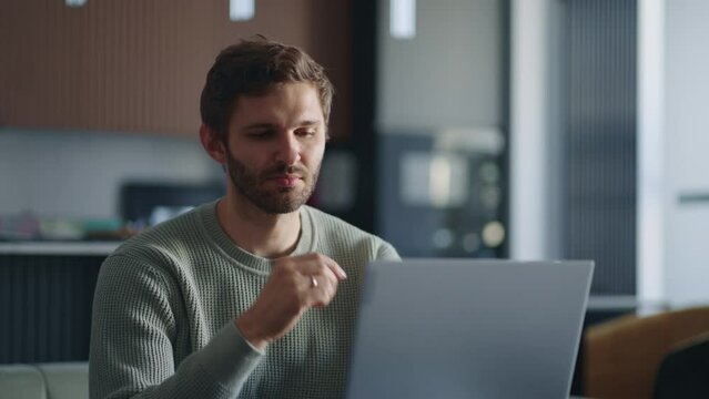 pensive man is working with laptop at home at evening, writing message in online chat and working on book. Business man laptop touches chin thinks over strategy work remotely from home, creative job