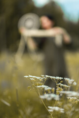 An attractive woman in a summer field with a dream catcher. Blurred photo. Vertical photo.