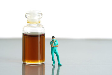 Miniature people toy figure photography. Urine test concept. A nurse standing in front of ampoule bottle with brown orange urine