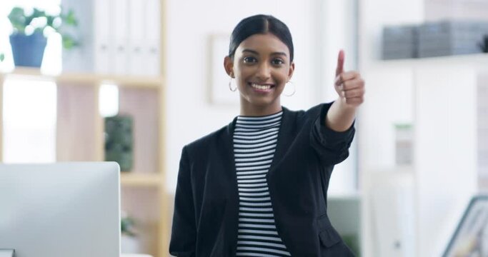 Thumbs up as a thank you, yes or success hand gesture of a business woman in an office. Portrait of an Indian company employee with a smile happy about career win, completed work goal or job success