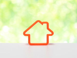 Orange home icon symbol. House icon on white table with green background