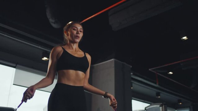 Young woman working on her fitness, skipping with a jump rope at the gym.