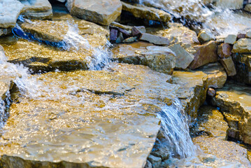 Beautiful cool and refreshing running stream along the stones and rocks on a bright summer day.Closeup.