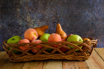 Fruits in wicker basket on wooden table.