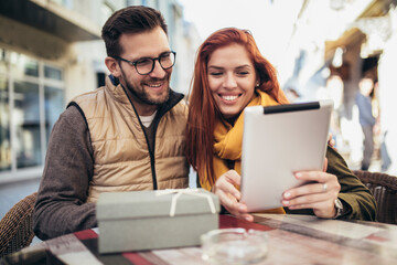 Happy young couple using a digital tablet together at a coffee shop.
