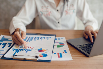 business man analyzing work on desk with job graphics and The laptop is a tool for analyzing tasks.