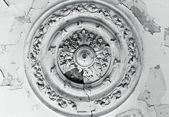 The old ceiling with crumbling plaster is decorated with stucco elements in the Baroque style - rosettes, volutes, floral ornaments.