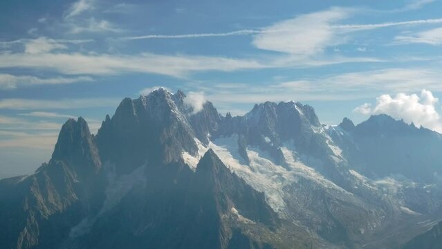 snow-capped rocky mountains with blue sky and clouds with a natural light in the alps. Static shoot.