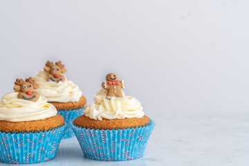 Christmas Cupcakes with Gingerbread and Reindeer Toppers on White Background with Copy Space