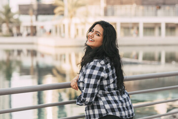 A charming Indian woman laughs while walking around the city. A positive girl in the city, positive emotions. The concept of urban life