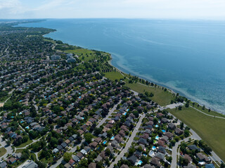 A high, aerial view above a large residential neighbourhood next to a lake.