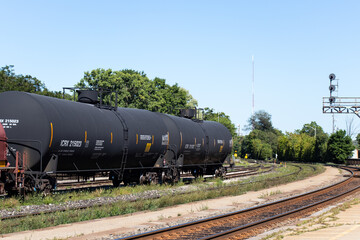 Fototapeta na wymiar Three oil tanker freight train cars are seen together, stationary in a rail yard during the day.