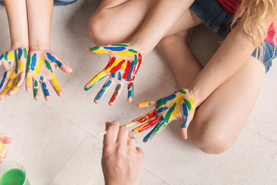 Hands of a child in paint. kids hands covered with paint top view.  teacher works with children according to the Montessori method and paints their hands. 