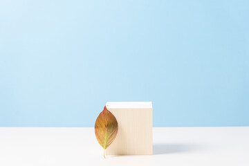 Wood podium on blue background with colorful autumn leaf.  Concept scene stage showcase, product, promotion sale, presentation, beauty cosmetic. Wooden stand studio empty. Minimal composition