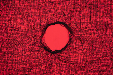 Large Textile mesh hole in the center on red background. Breakthrough concept.