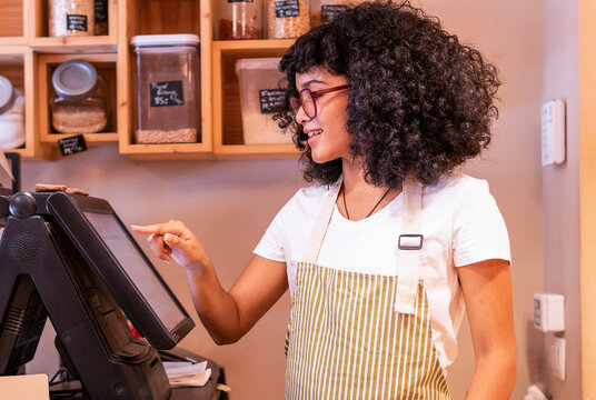 Young black woman using cash register in shop