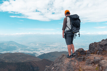 Traveler with backpack standing on top of mountain