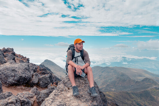 Pensive traveler with backpack sitting on top of mountain