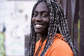 Headshot of a young adult woman of African ethnicity with dreadlocks hairstile smiling and looking...