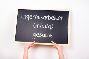 Zwei Hände halten eine Tafel auf der Lagermitarbeiter gesucht steht