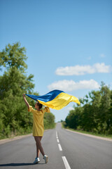 woman with the Ukrainian flag, waving ukrainian flag, a girl with ukrainian flag on the road
