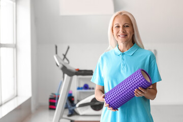 Mature physiotherapist with foam roller in rehabilitation center