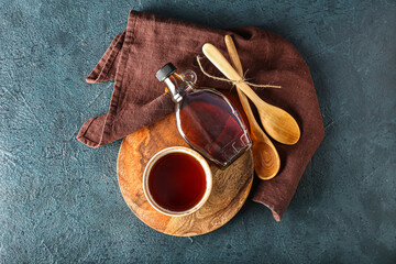 Composition with bowl and bottle of tasty maple syrup on dark color background