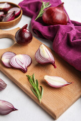 Wooden board with cut red onion on light background, closeup
