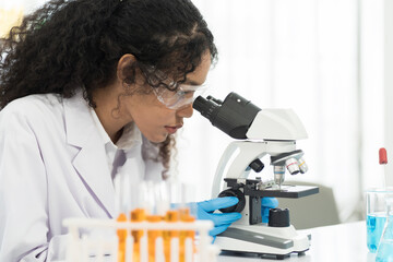 Woman scientist looking through microscope doing analysis for germs and bacteria of test sample in the laboratory. Female specialist working with biotechnology research with microscope
