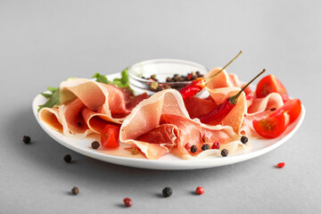 Plate of delicious jamon and peppercorns on light background