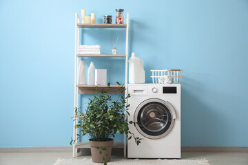 Interior of stylish laundry room with washing machine, shelving unit and houseplant