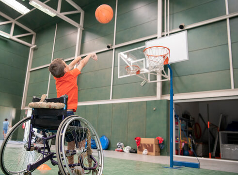 Boy in a wheelchair throwing the ball into the basketball basket