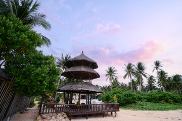 Tropical landscape with wooden bungalow on sand beach.