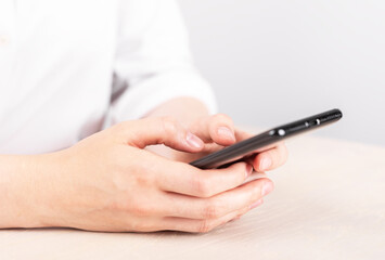 Woman hands closeup texting message at phone. Female sitting at table and using messenger for chatting, sharing information in blog or searching data on Internet