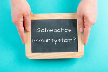 Weak immune system is standing in german language on a chalkboard, healthy eating and lifestyle...