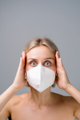 Portrait of a young woman in a medical mask on a grey background.
