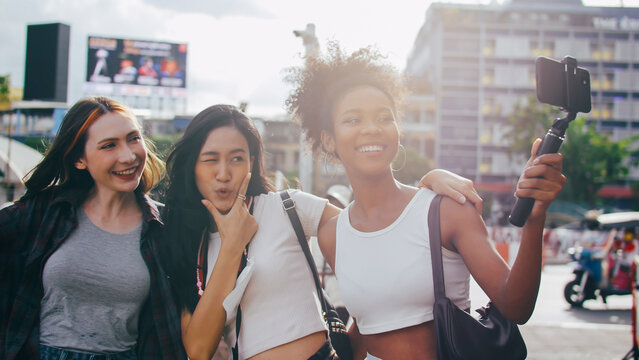 A group of multi-ethnic female friends enjoying the city tour. Young tourists having fun taking pictures together.