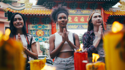 Obraz na płótnie Canvas A group of multi-ethnic female friends praying at a Chinese shrine in Bangkok, Thailand.