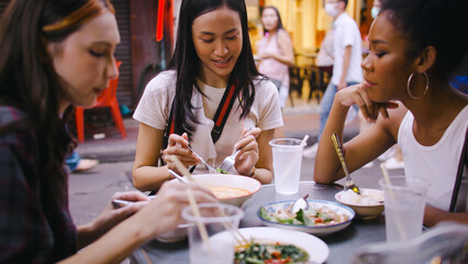 A group of multi-ethnic female friends enjoying street food on Yaowarat Road or Chinatown in Bangkok, Thailand.