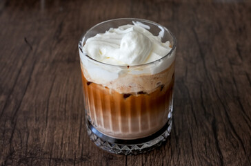Glass with Ice Mocha with whipped cream. Cold coffee drink on a brown background.
