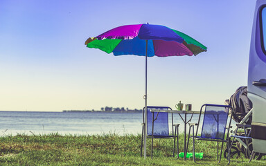 Umbrella with chairs at campervan on beach