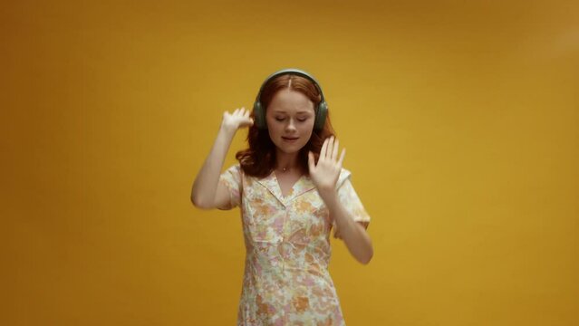 A young ginger white woman wearing headphones dancing  having a good time enjoying the music