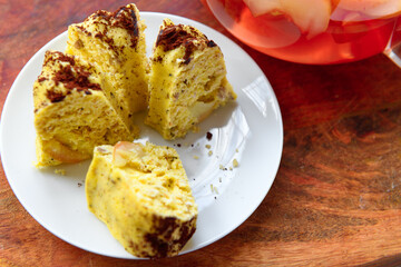 slices of homemade cake on a plate and glass teapot with stewed fruits - apples, plums and strawberries on a wooden background, concept of fresh fruits and healthy food
